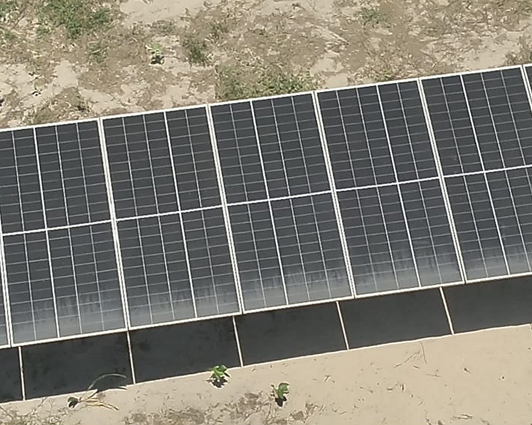 Imagem visual aérea de uma fileira de módulos fotovoltaicos, sem sinal aparente de defeito